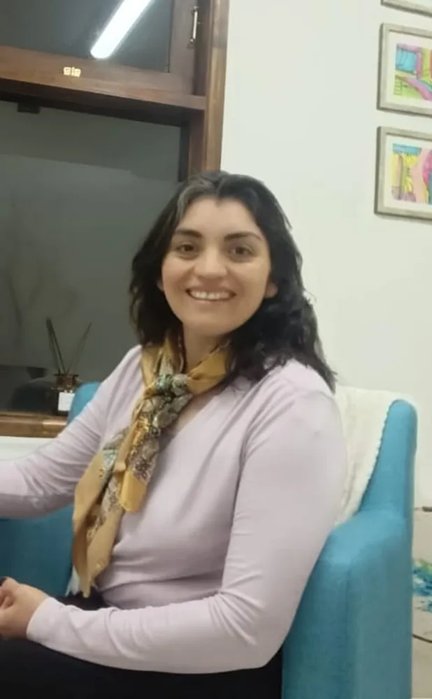Maritza Rivas sonríe sentada en un sillón turquesa de su consulta