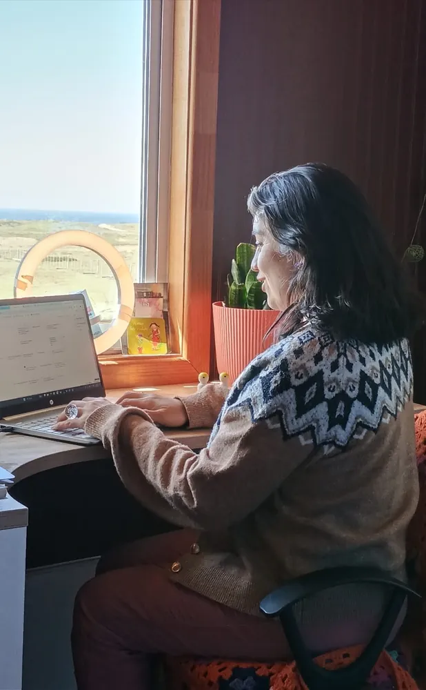 Maritza Rivas trabajando en su escritorio, junto a una ventana con vista a la estepa y al mar